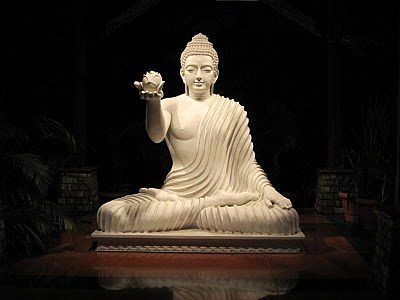 The Buddha in full lotus meditation posture, right hand offering a lotus to you.